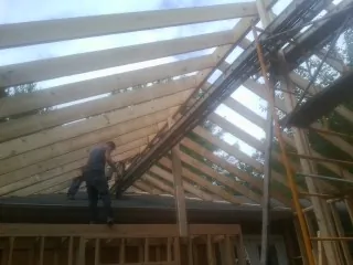 Rafters going up over a new addition with a worker on the wall in Ephraim