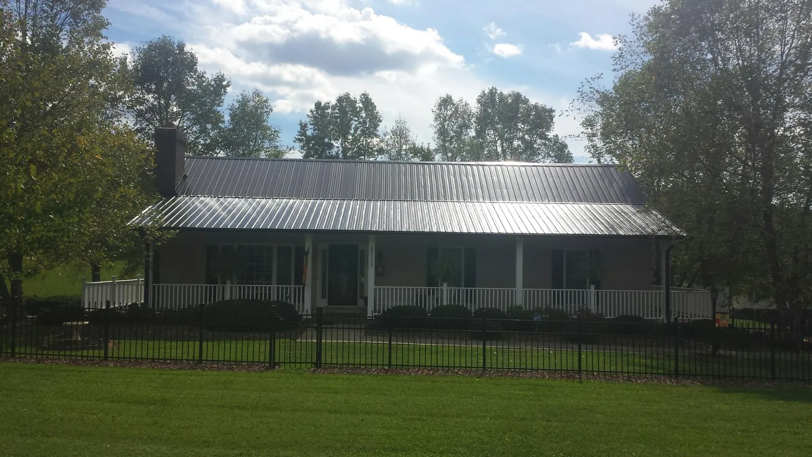Gray metal roof on a brick ranch with a full width front porch — Gutter Guard Installation work by our crew in Ephraim